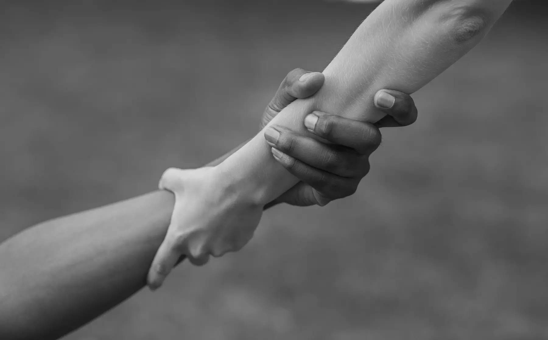 Dos manos agarrándose en un fuerte y solidario apretón de manos, representado en una fotografía en blanco y negro.